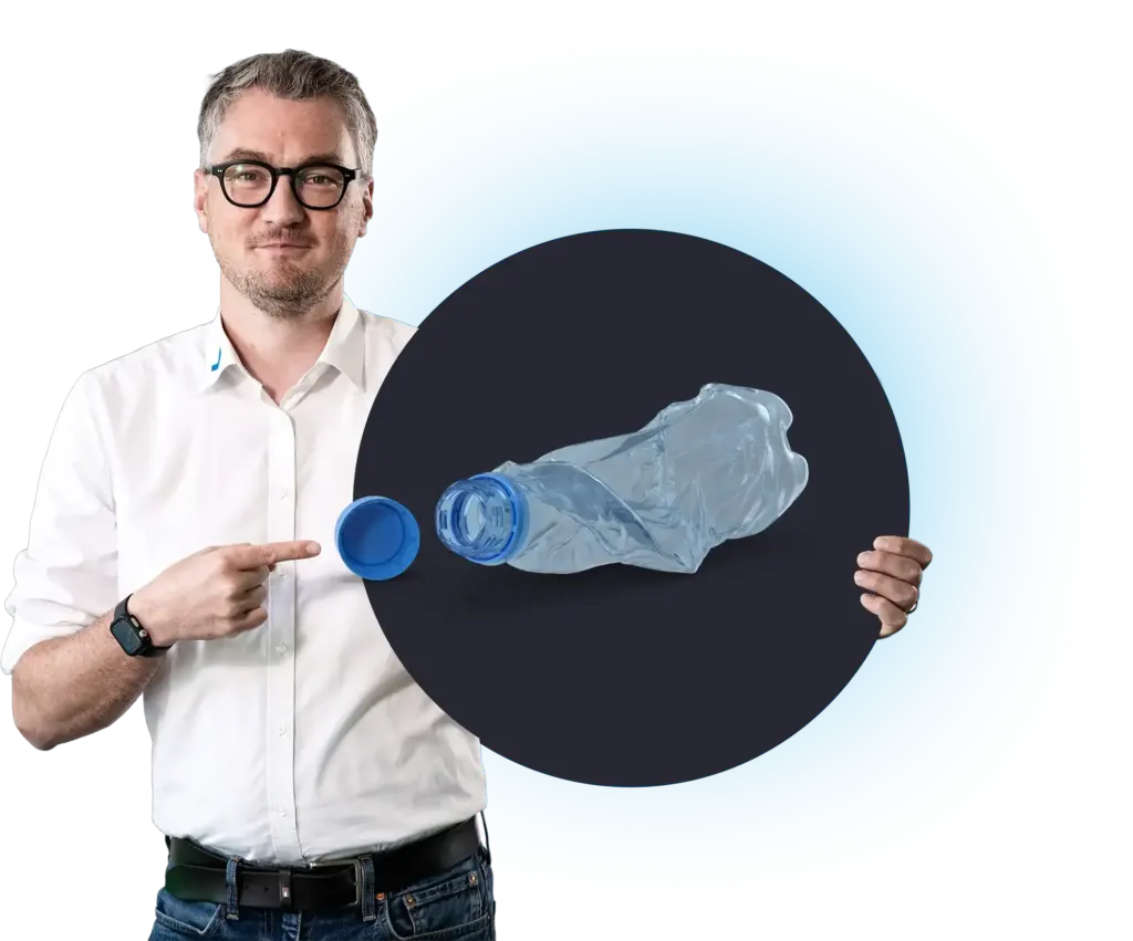 A man points to a crumpled plastic bottle with a cap, MODUL6 RZ.