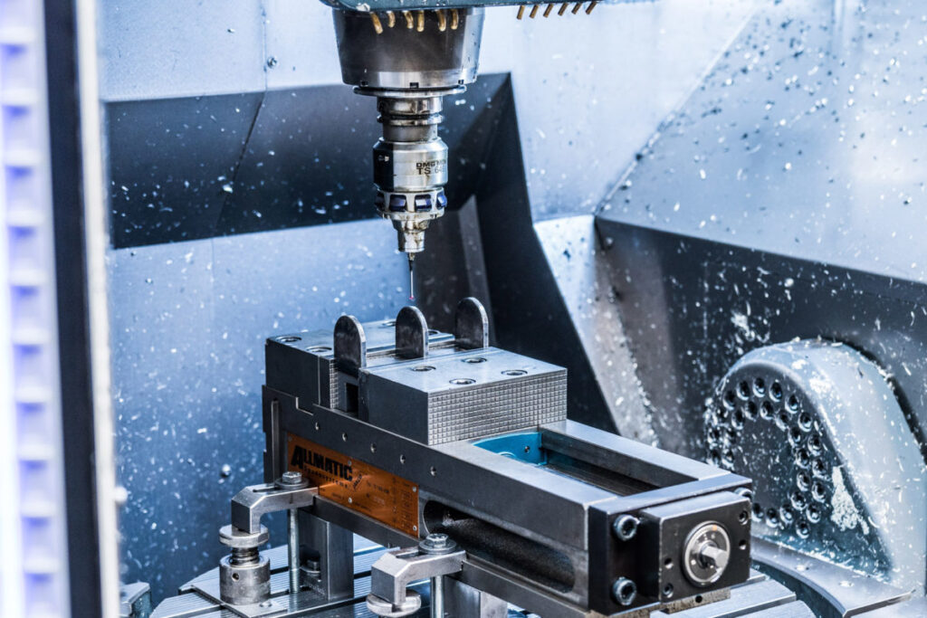 CNC MACHINING: A milling machine is machining a metal block in a workshop.