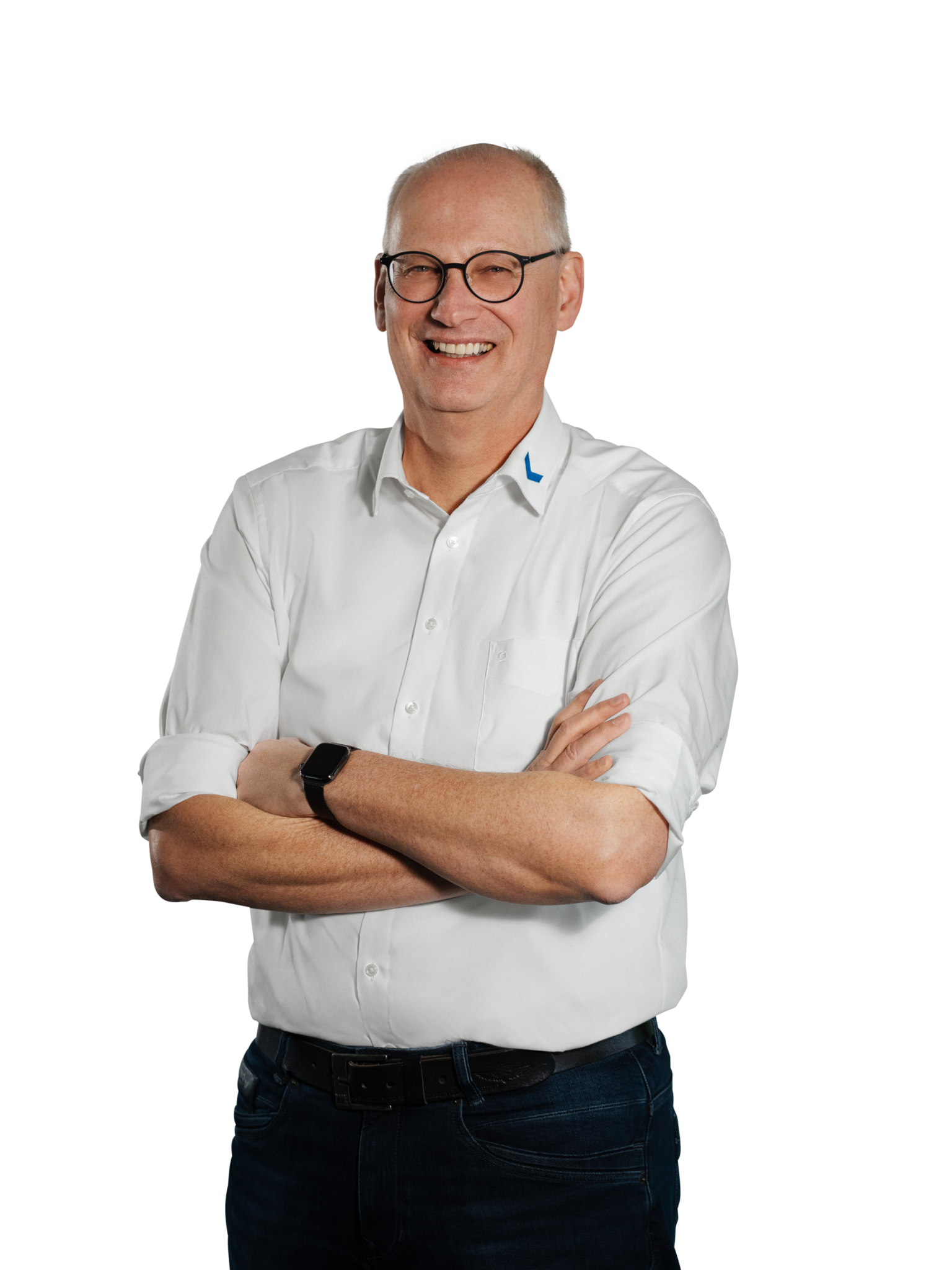 A man in a white shirt, with his arms crossed and wearing glasses, is smiling.