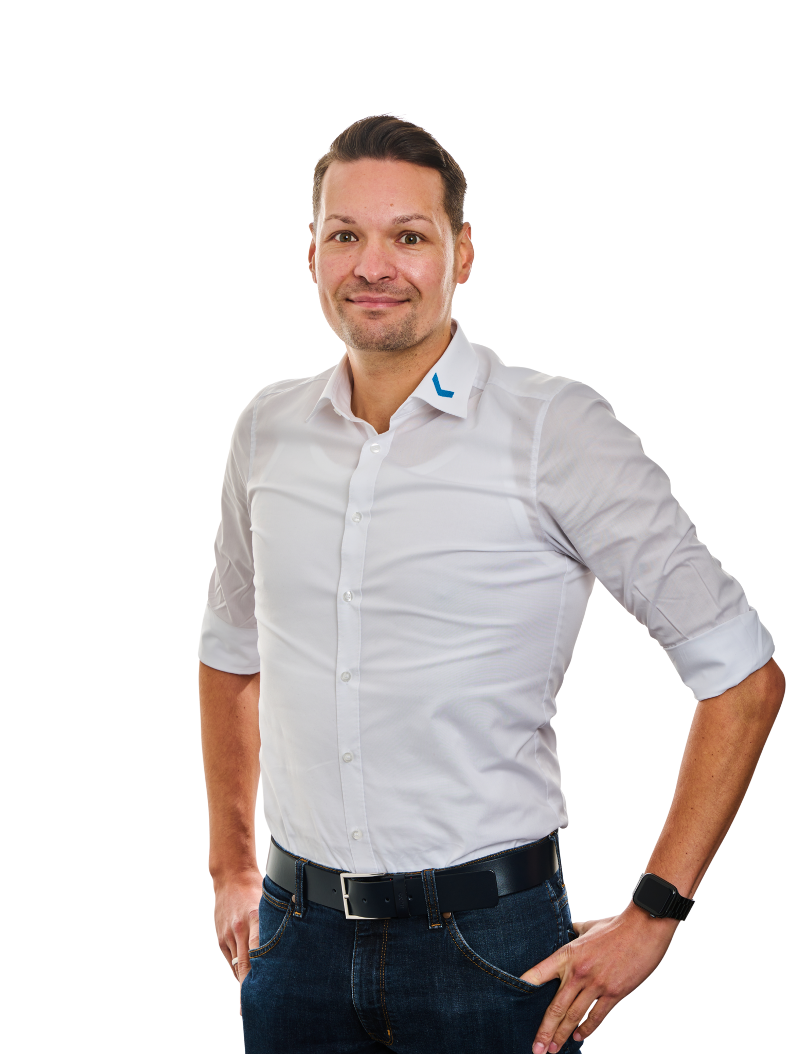 Mann in weißem Hemd und Jeans mit Händen in den Taschen.