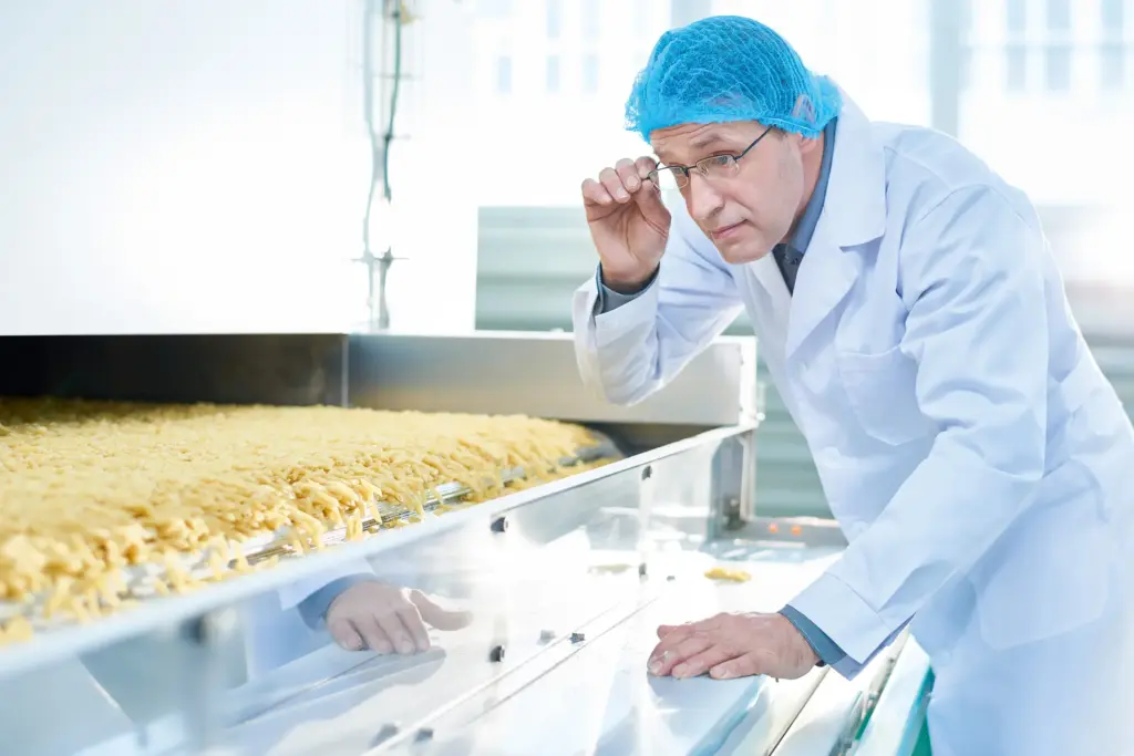 A man in protective gear inspects food production.