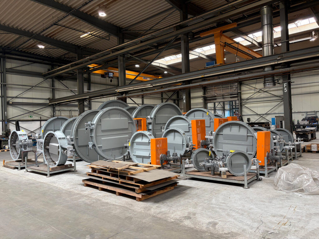 Overview of 25 industrial dampers and gate valves in a production hall, ready for acceptance at a cement plant