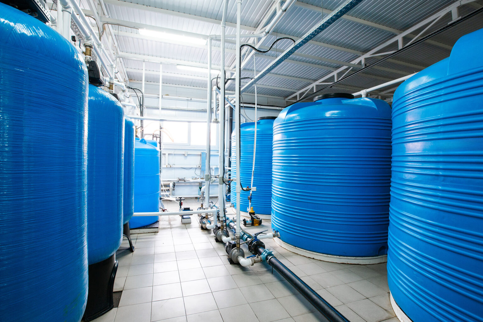 Several large blue tanks for precipitation and flocculation in the water treatment process in the industrial building