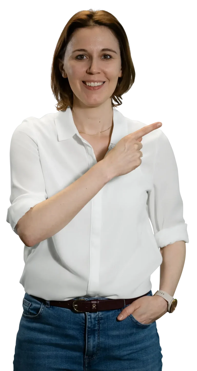 A woman in a white shirt and jeans is smiling and pointing to the side.