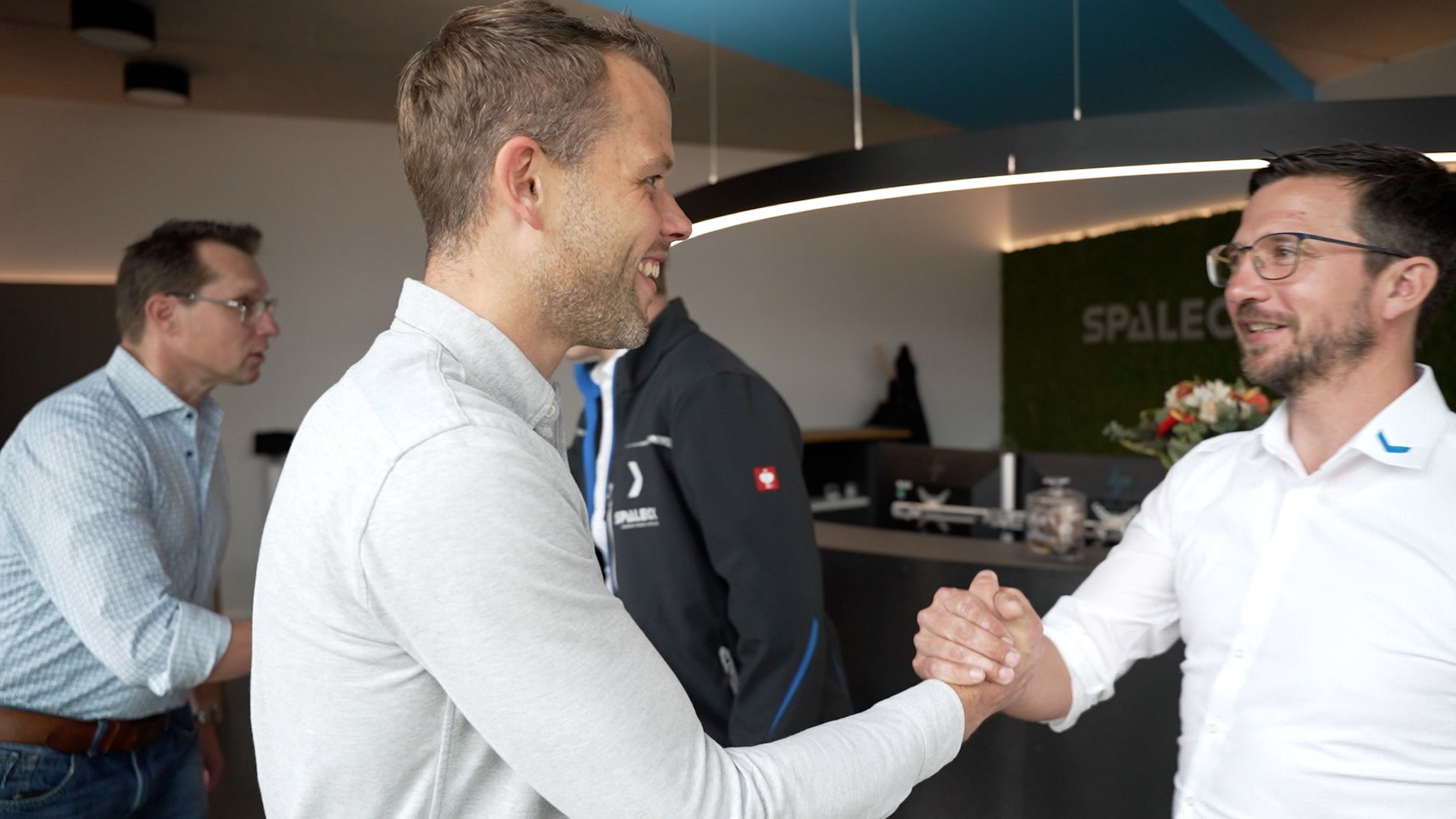 Two men shake hands in a modern office.